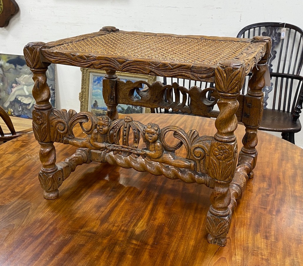 A Jacobean revival carved oak cane seat stool, width 52cm, depth 39cm, height 43cm.